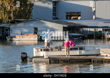 L'homme et de deux femmes dans le port de Mount Dora prépare à prendre un bateau ponton amarré dehors pour une croisière au coucher du soleil sur le lac Dora. Banque D'Images