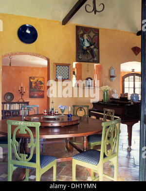 Chaises peintes en vert clair à table circulaire avec lazy susan en espagnol villa salle à manger avec piano Banque D'Images