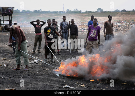 Adolescents brûler les câbles des ordinateurs et autres appareils électroniques pour récupérer le cuivre près du bidonville Agbogbloshie à Accra, Ghana Banque D'Images