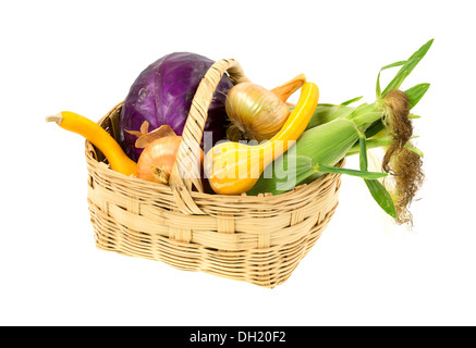 Un grand panier en osier rempli d'un assortiment de légumes fraîchement cueillis du jardin sur un fond blanc. Banque D'Images