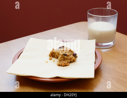 L'avoine et aux raisins à moitié mangé cookie avec demi verre de lait bu Banque D'Images