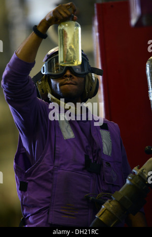 Manœuvriers Aviation Mate (fossiles) Airman Anthony Long de Chester, Pennsylvanie sur le navire d'assaut amphibie USS Bataan (DG 5) inspecte les échantillons de carburant pour les impuretés au cours d'un ravitaillement en mer avec reconstitution de la flotte oiler USNS Big Horn (T-AO 198) Banque D'Images