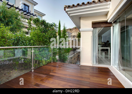 Balcon en bois avec rampe en verre sur villa récemment construite dans la ville côtière du sud de l'Espagne Banque D'Images