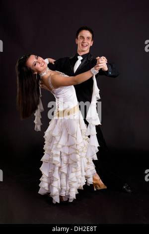 Les jeunes danseurs de bal en costumes officiels posant sur un fond uni dans un studio Banque D'Images