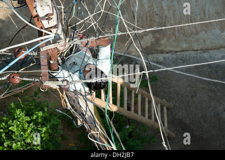 Regardant vers le bas sur un Indien Electrician working en place d'un pylône d'électricité dans les rues de Puttaparthi, Andhra Pradesh, Inde Banque D'Images