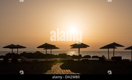 Parasols sur la plage au coucher du soleil Banque D'Images