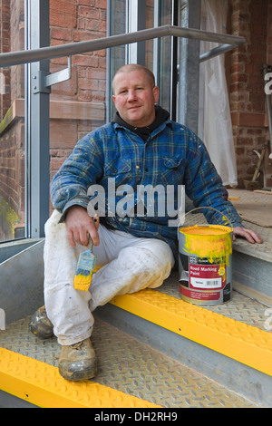 Anthony McAuley, peintre, travaillant sur la bordure jaune de la nouvelle en colimaçon, Fairfield, Govan Road, Glasgow, Scotland, UK Banque D'Images