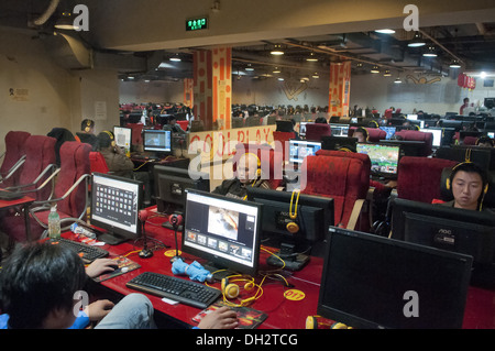 De jeunes Chinois, hommes et adolescents, s'assoient devant de grands écrans LCD d'ordinateur en utilisant des micro-casques et en jouant à des jeux en ligne et en suivant des flux en direct dans un Wangba(r), qui se traduit par un cybercafé à Beijing, en Chine. PRC. © Olli Geibel Banque D'Images