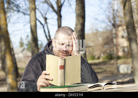 Homme lisant un livre à l'extérieur sur un banc Banque D'Images