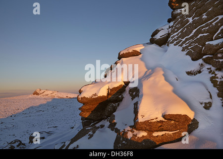 Un hiver enneigé juste avant le coucher du soleil, sur les sommets rocheux des landes ; dans le parc national de Dartmoor, Devon, dans le sud-ouest de l'Angleterre, en Grande-Bretagne. Banque D'Images