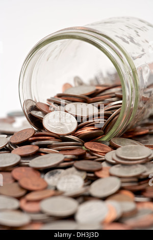 Pot mason de verre plein de changement de poche lâche tomber sur fond blanc Banque D'Images