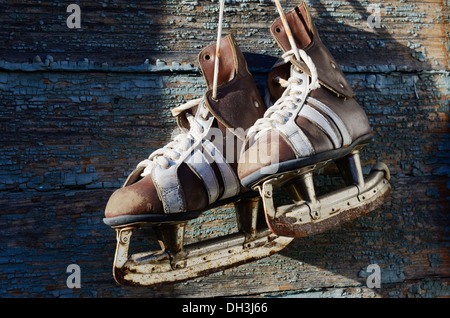 Vintage paire de patins à glace mens accrochée à un mur en bois Banque D'Images