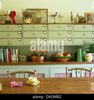 Table et chaises en pin en face de vert pâle peint placard de rangement tiroirs équipés d'étroit ci-dessous wall Banque D'Images