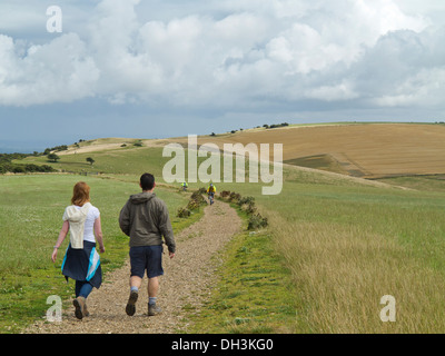Jeune homme et femme marche sur sentier South Downs près de Ditchling Beacon Sussex avec les cyclistes en contexte le week-end d'été Banque D'Images