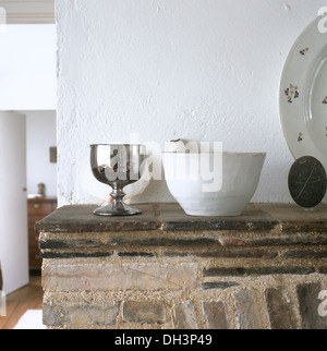 Gobelet d'argent et simple white ceramic bowl sur la cheminée en pierre Banque D'Images