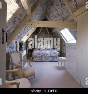 Blanc +bleu Toile de Jouy et coordonnées capot lit dans une chambre mansardée avec tapis blanc et des poutres en bois rustique Banque D'Images