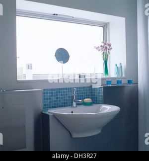 Construit en évier avec sol carrelé bleu splash back sous fenêtre avec petit miroir sur le stand Banque D'Images