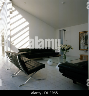 Chaises en cuir noir Barcelona de Mies van der Rohe autour d'une table basse en verre dans des décors minimalistes salon avec carrelage blanc Banque D'Images