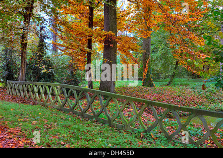 La clôture en pierres sur petit ruisseau et arbres avec de luxuriants feuillages colorés en automne dans le parc de Racconigi, au nord de l'Italie. Banque D'Images