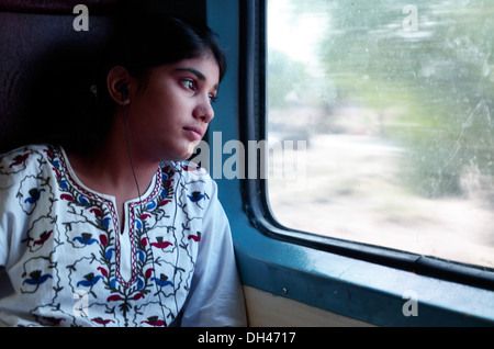 Fille d'écouter de la musique et regarder par la fenêtre du train Jodhpur Rajasthan Inde Asie M.# 704 Banque D'Images