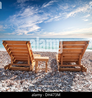 Deux transats en bois debout sur la côte de la mer Adriatique sous ciel nuageux spectaculaire Banque D'Images