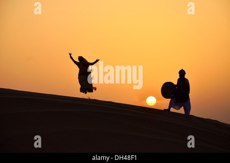 L'homme jouant des percussions et danse femme sautant au coucher du soleil le Rajasthan en Inde Asie M.# 704J Banque D'Images