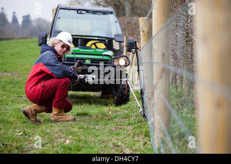 Un agriculteur utilise le treuil sur un John Deere Gator pour tendre quelques clôtures UK Banque D'Images