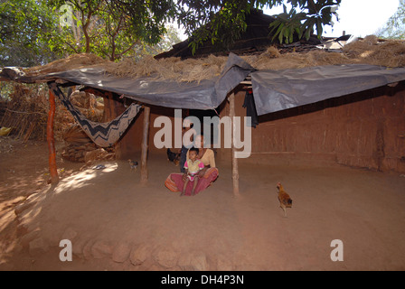 Femme avec ses enfants assis à l'extérieur hut, Tribu Bhil, Madhya Pradesh, Inde Banque D'Images