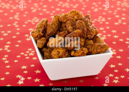 Brûlé d'amandes dans un plat blanc sur fond rouge Banque D'Images