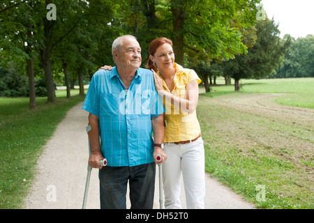 Femme et un vieil homme avec des béquilles en flânant dans le parc Banque D'Images