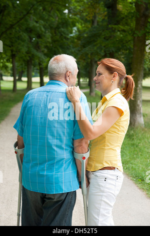 Femme et un vieil homme avec des béquilles en flânant dans le parc Banque D'Images