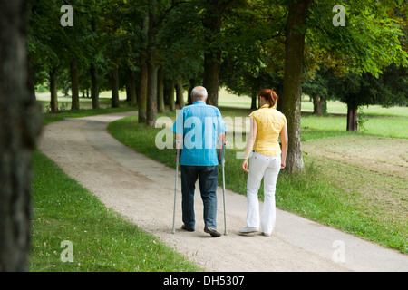 Femme et un vieil homme avec des béquilles en flânant dans le parc Banque D'Images