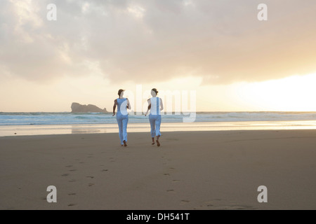 Deux femmes le long de la plage au coucher du soleil Banque D'Images