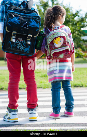 Des enfants portant des sacs de l'école sur le chemin de l'école Banque D'Images