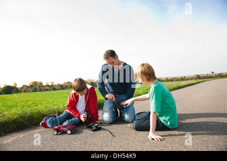 Père bricoler sur un modèle de voiture télécommandée avec ses fils Banque D'Images