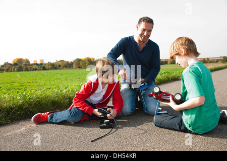 Père bricoler sur un modèle de voiture télécommandée avec ses fils Banque D'Images