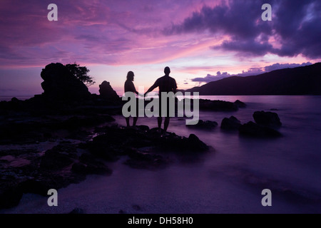 Couple debout sur la plage après le coucher du soleil, se tenant les mains, Kuta Lombok, Lombok, Nusa Tenggara Barat Province Banque D'Images