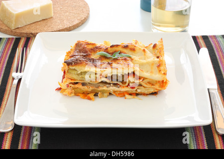 Lasagnes végétariennes avec aubergines, courgettes, patates douces et sauce tomate sur une plaque blanche. Banque D'Images