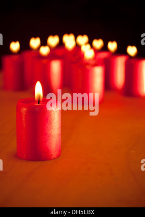 Bougie rouge brûler tranquillement, avec des bougies sur arrière-plan avec les cœurs à flammes - symbole de la saison pour la paix et l'amour Banque D'Images