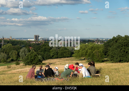 Groupe d'amis assis sur l'herbe sur la Colline du Parlement, Hampstead Heath, London, UK Banque D'Images