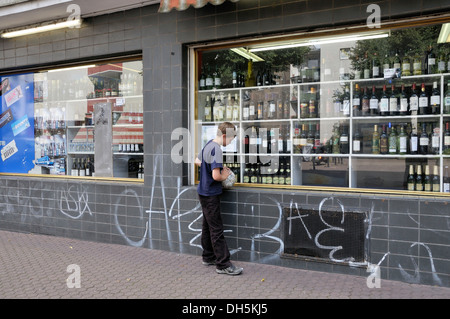 Garçon, 10 ans, à la recherche de boissons alcoolisées dans la fenêtre d'une des boissons alcoolisées, Cologne, Rhénanie du Nord-Westphalie Banque D'Images