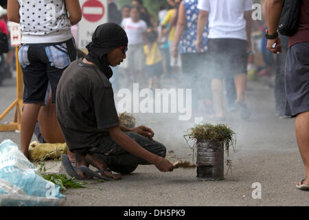 Calamba,Cimetière,la ville de Cebu aux Philippines. 1er novembre 2013. La Toussaint aux Philippines et un temps pour se souvenir de la Philippine Catholique et rendre hommage à leurs êtres chers décédés.ici à la sortie des feux d'un homme pris de mauvaises herbes de l'intérieur du cimetière. Ceux qui peuvent passer sur la sortie de fumée qui est censé pour enlever tout les mauvais esprits. Dans le dialecte Cebuano local c'est ce qu'on appelle 'Palina'. Credit : gallerie2/Alamy Live News Banque D'Images