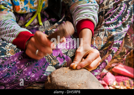 Femme berbère frappant les écrous d'argan sur une enclume de pierre avec une roche pour se rendre à des noyaux pour la préparation de l'huile d'argan, Anti-Atlas Banque D'Images