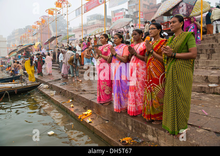 Cinq femmes en saris colorés dans la prière, sur les rives de la rivière du Gange, Varanasi, Uttar Pradesh, Inde Banque D'Images