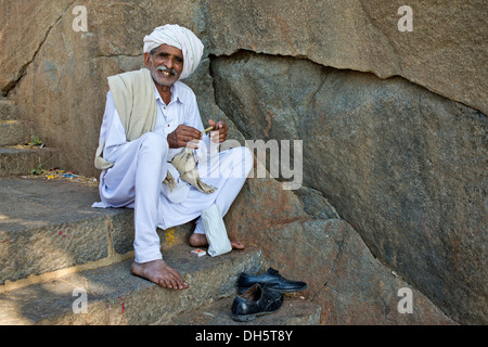 Un pèlerin vêtu de blanc est assis sur l'escalier menant au temple sur la sainte montagne de Girnar, Junagadh, Gujarat Banque D'Images