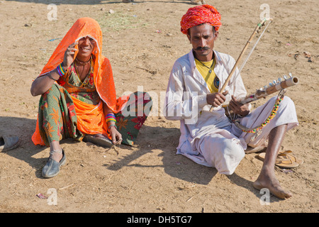 Les hommes indiens avec un turban et porter le vêtement pour hommes traditionnel dhoti, lecture d'un sitar, femme avec un sari coloré assis Banque D'Images