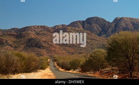 Dans l'arrière-pays australien de la route bordée d'arbres bas en direction de West MacDonnell Ranges près d'Alice Springs dans le Territoire du Nord Banque D'Images