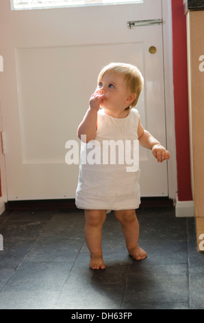 Fille de 9 mois, apprendre à se lever et marcher sur plancher de la cuisine. Angleterre, Royaume-Uni. Banque D'Images