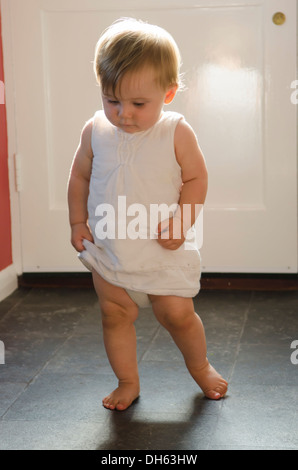 Fille de 9 mois, apprendre à se lever et marcher sur plancher de la cuisine. Angleterre, Royaume-Uni. Banque D'Images