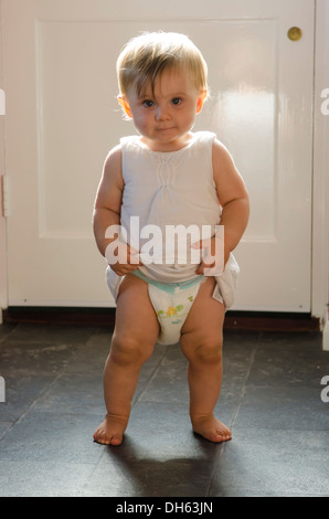 Fille de 9 mois, apprendre à se lever et marcher sur plancher de la cuisine. Angleterre, Royaume-Uni. Banque D'Images